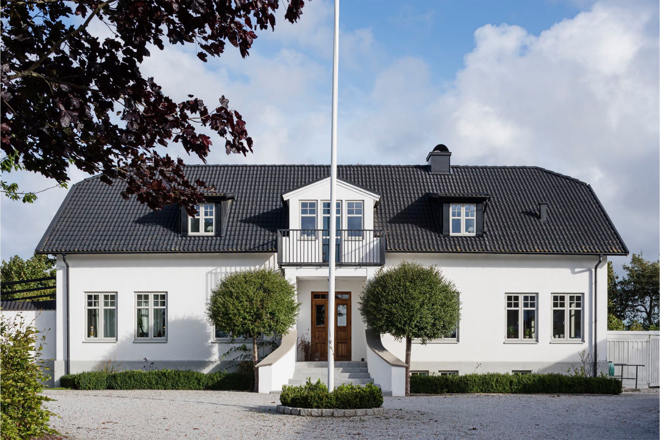 Vitt hus med trä aluminium fönster, i ljusgrå färg med vit insida. Ytterdörr i ek