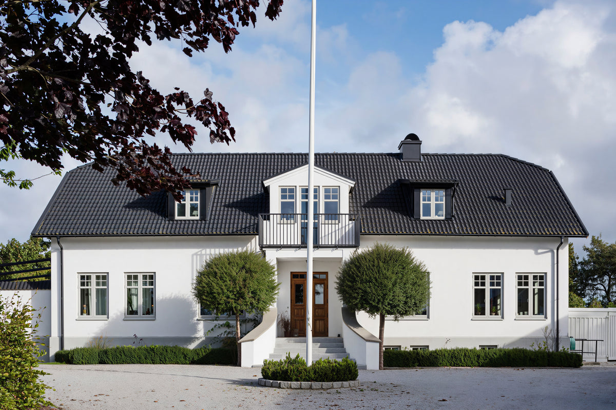 Vitt hus med trä aluminium fönster, i ljusgrå färg med vit insida. Ytterdörr i ek