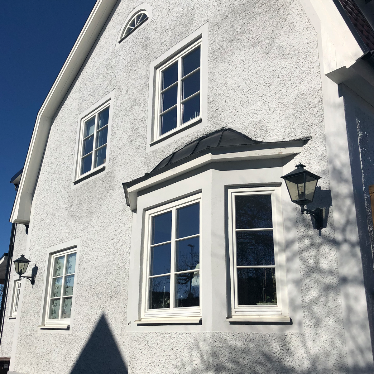 Klassiska fönster med spröjs på en putsad villa