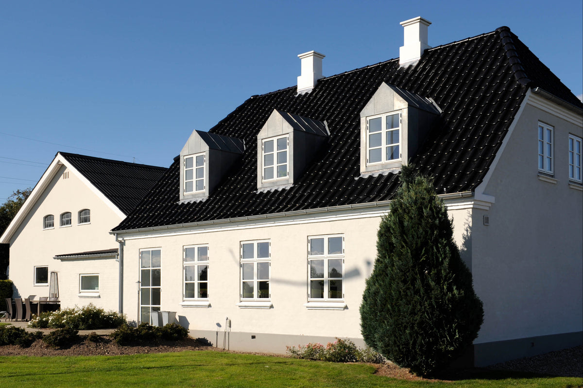 Vitt hus med måttanpassade energieffektiva fönster i klassisk stil.